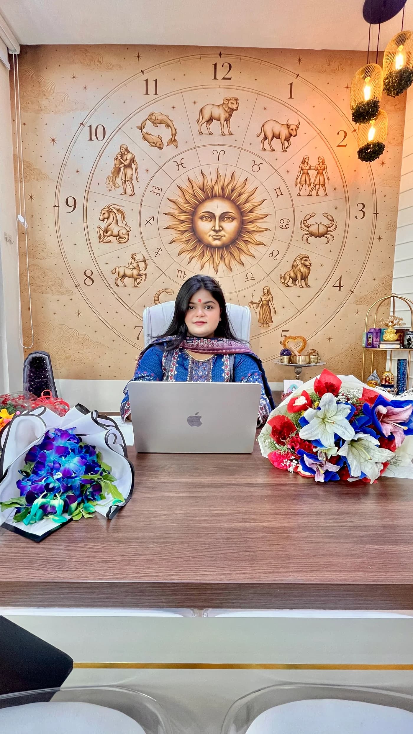 Shivangi Rai in her consultation space, seated beneath a gold zodiac mural